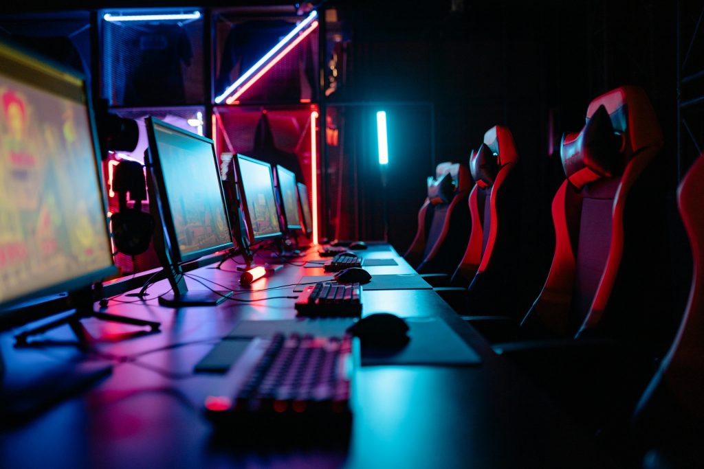 An immersive gaming room with neon lights, computers, and gaming chairs ready for a tournament.